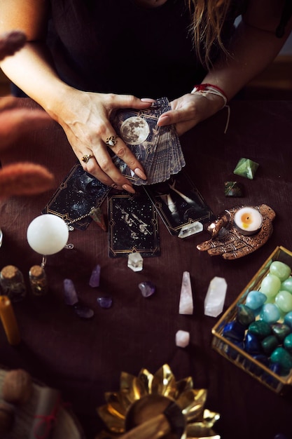 Foto eine frau zeigt das tarotkarten-deck, das bereit ist, mit dem lesen zu beginnen, auf ihrem hexen-altar mit mehreren halbedelsteinen auf dem tisch