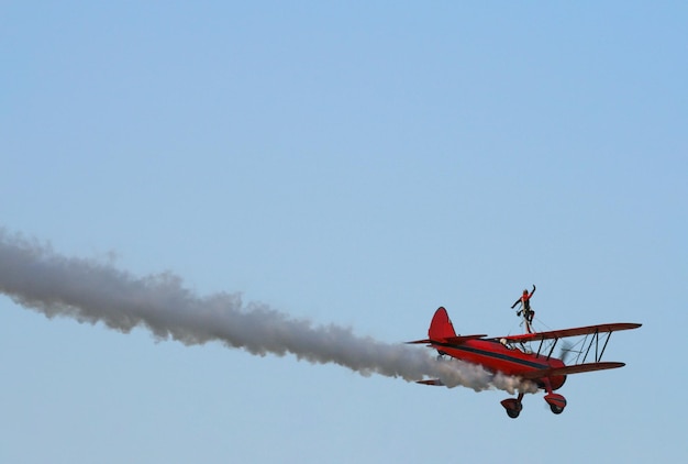 Eine Frau zeigt Tricks auf dem Flügel eines Retro-Flugzeugs am Himmel