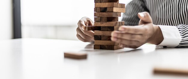 Eine Frau zieht einen Holzblock aus einer Reihe und bricht ihn nicht ab, wie ein gutes Geschäft zu führen und Probleme zu lösen. Das Konzept der Unternehmensführung auf Risiko.