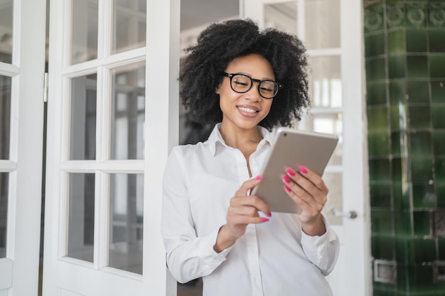 Eine Freiberuflerin mit Brille im Büro arbeitet mit einem Tablet an einem Startup-Projekt