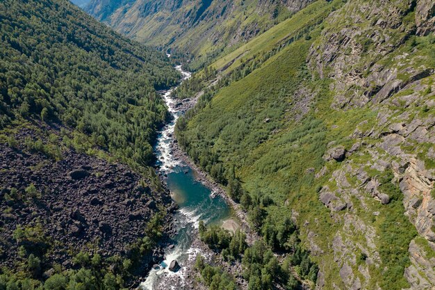 Eine friedliche Landschaft mit felsigen Hügeln und einem schnell fließenden schmalen Bach entlang. Vogelperspektive.