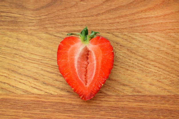Eine frische Erdbeere in Form eines Herzens halbiert auf einem hölzernen Hintergrund