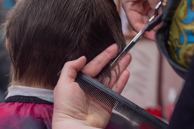 Eine Friseurin schneidet einem Jungen mit einer Schere die Haare