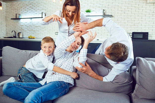 Eine fröhliche Familie spielt auf der Couch im Zimmer