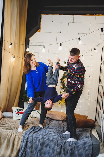 Eine fröhliche junge Familie mit einem kleinen Kind ruht zu Hause am Weihnachtsbaum Familienpaar mit Weihnachtsdekoration zu Hause Weihnachten und Neujahr Zeit zum Feiern