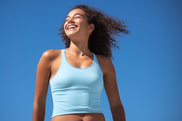 Eine fröhliche junge Frau in einem Casual-Tanktop vor einem himmelblauen Hintergrund