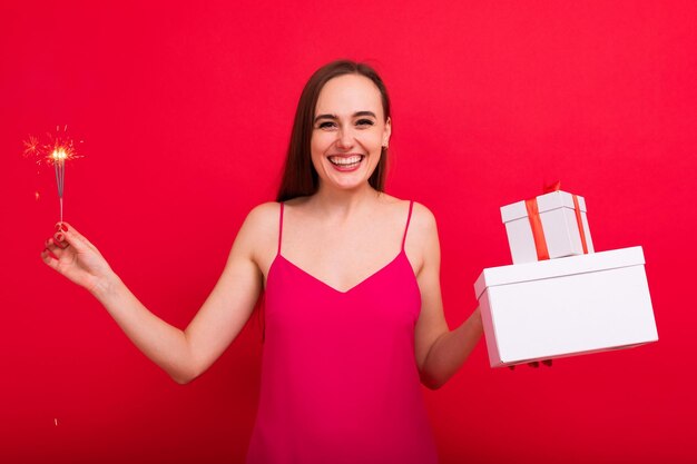 Eine fröhliche junge Frau mit Wunderkerzen und Geschenken in Kartons Weihnachtsfeier