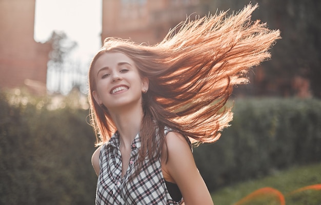 Eine fröhliche Studentin geht über den Campus und der Wind weht ihr durch die Haare