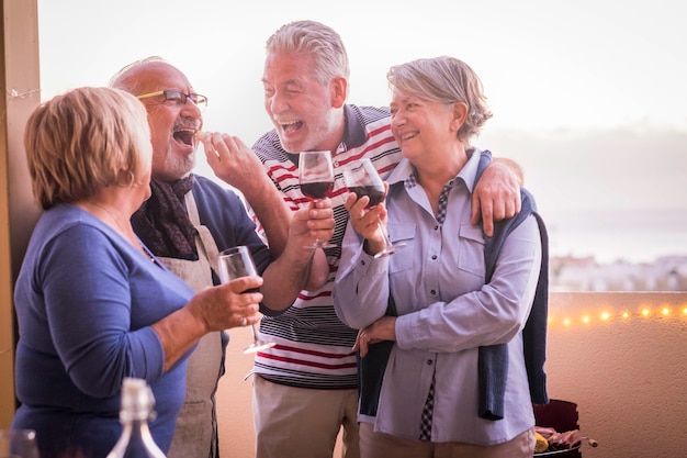 Eine fröhliche und lächelnde Gruppe von Erwachsenen genießt die Cocktail-Freizeitaktivität im Freien auf der Terrasse. Sommersaison und lachen. schöne Rentner im lustigen Lebensstil zusammen in Freundschaft. cele