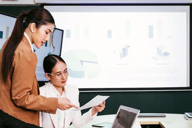 Eine fröhliche und selbstbewusste asiatische Geschäftsfrau sitzt während des Meetings im Besprechungsraum und bespricht Dokumente ihrer Bürokollegen. Asiatische Geschäftsfrauen übernehmen die Führungsrolle bei dem Meeting