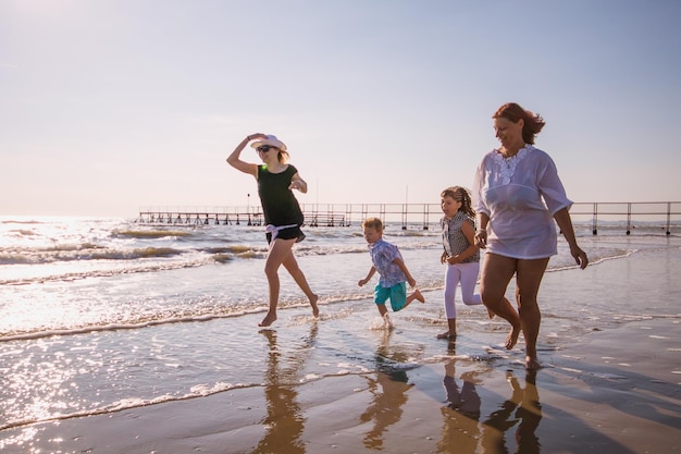 Eine ganze Familie läuft am Strand gegen den Himmel.