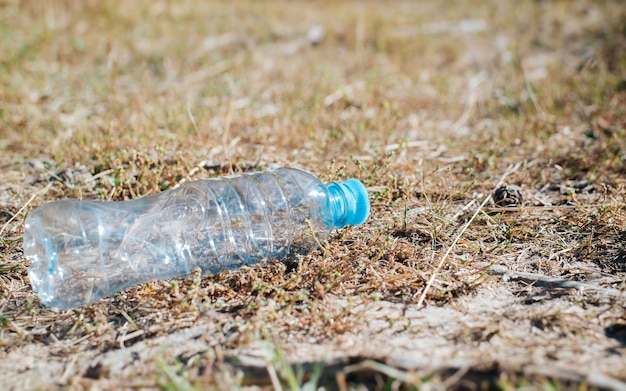 Eine gebrauchte Plastikflasche, die auf einem Pfad im Freien liegt. Selektiver Fokus der Nahaufnahme mit niedrigem Winkel