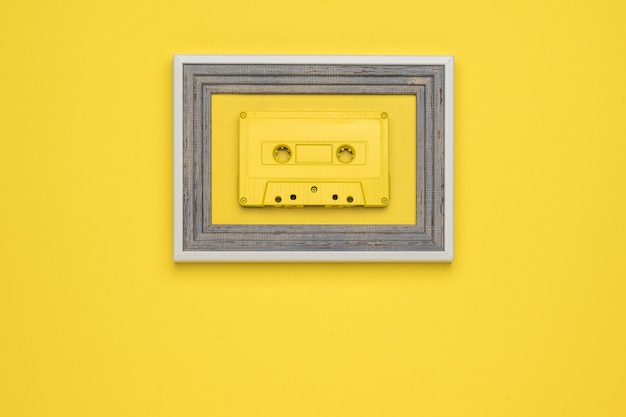 Foto eine gelbe bandkassette in einem rahmen auf gelbem grund. flach liegen.