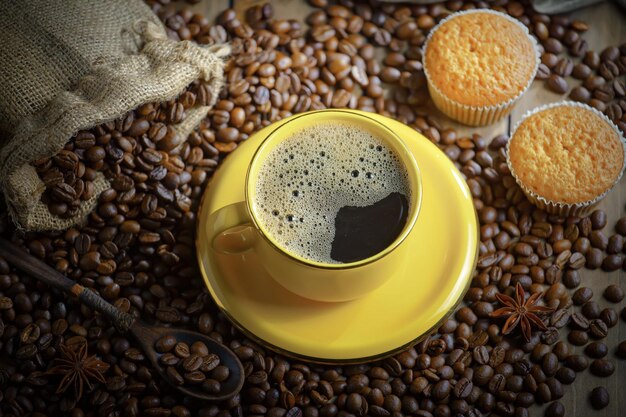 Eine gelbe Tasse Kaffee steht auf einem Haufen Kaffeebohnen und einem Haufen Kaffeebohnen.