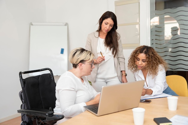 Eine Geschäftsfrau im Rollstuhl mit Behinderung arbeitet mit ihren Kollegen in einem Büro an der Analyse von Daten