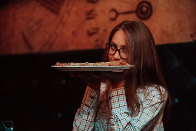 Eine Geschäftsfrau in der Mittagspause, die Pizza in einem modernen Restaurant isst. Selektiver Fokus. Foto in hoher Qualität