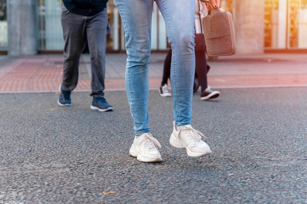 Eine Geschäftsfrau in Jacke und Jeans überquert die Straße und telefoniert