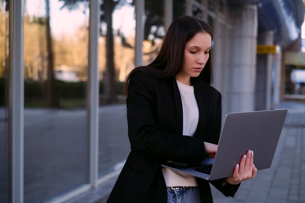 Eine Geschäftsfrau mit einem Laptop arbeitet im Freien und verkörpert die Rollen eines Büroangestellten
