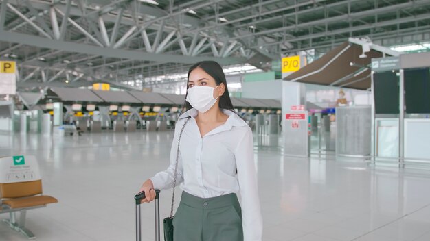 Eine Geschäftsfrau trägt eine Schutzmaske auf dem internationalen Flughafen und reist unter der Covid-19-Pandemie