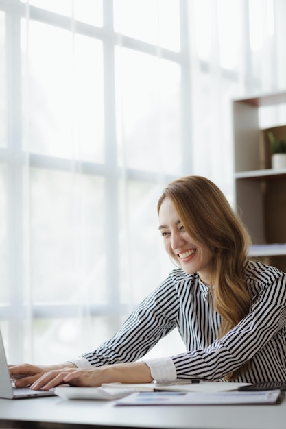 Eine Geschäftsfrau überprüft die Finanzdokumente des Unternehmens und verwendet einen Laptop, um über ein Messaging-Programm mit dem Chief Financial Officer zu sprechen Konzept des Finanzmanagements des Unternehmens