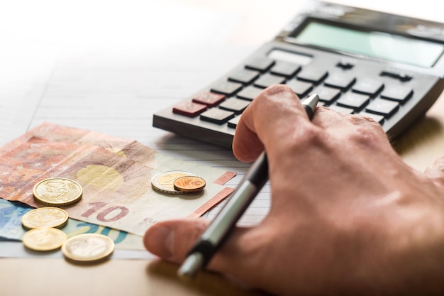 Eine geschnittene Hand, die am Schreibtisch Geld zählt