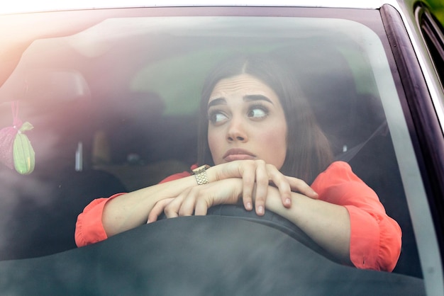 Eine gestresste Fahrerin sitzt in ihrem Auto, eine traurige Fahrerin fährt ein Auto, eine junge Frau steckt im Stau, eine verärgerte Frau sitzt im Auto, ein Mädchen steckt im Verkehr.
