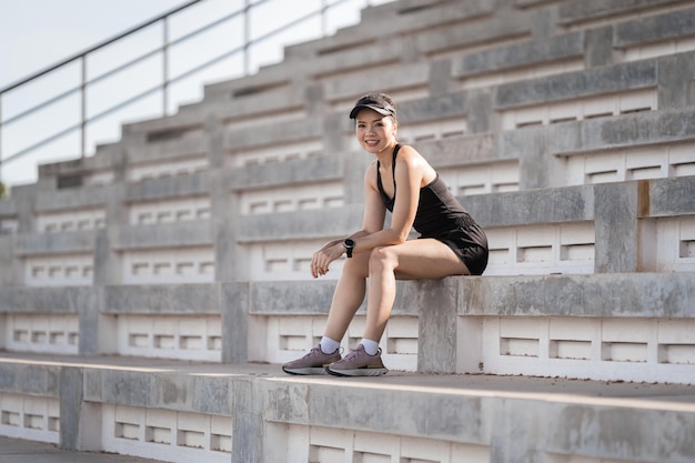 Eine gesunde erwachsene asiatische Frau, die auf die Betontreppe des Stadtstadions rennt, um den Körper zu stärken