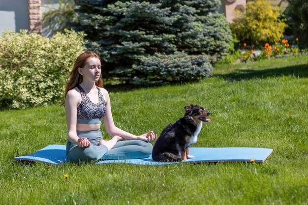 Eine gesunde Frau, die mit einem Welpen spielt, während sie auf einer Yogamatte sitzt