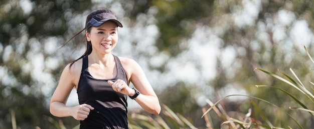 Eine gesunde, glückliche asiatische Läuferin in schwarzen Sportoutfits joggt