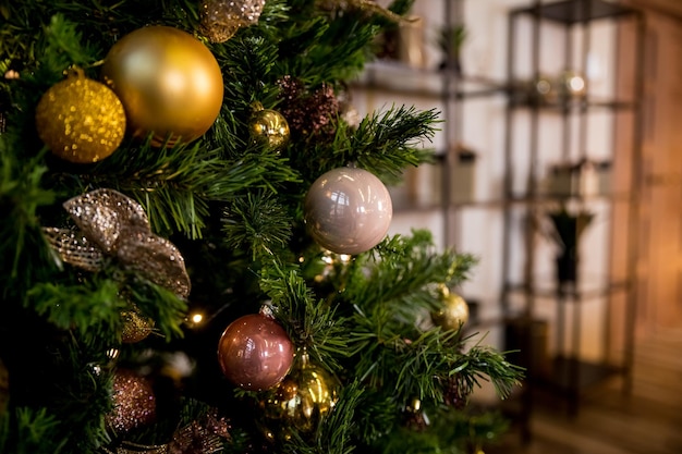 Eine glänzende goldene Kugel auf einem AstChristbaumschmuck Neujahrsschmuck in rosa und goldenen Tönen Herzlichen Glückwunsch zum Winterurlaub Vorbereitung für die Feier Postkarte