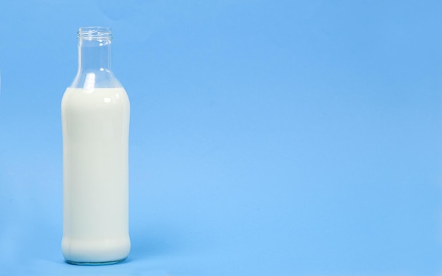 Eine Glasflasche Milch auf blauem Hintergrund mit Platz für Text