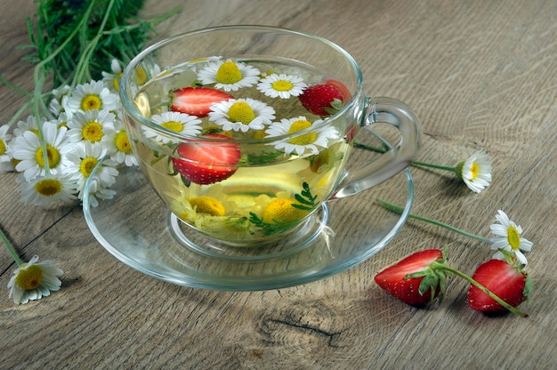 Eine Glasschale mit Tee und einem Strauß Gänseblümchen darin