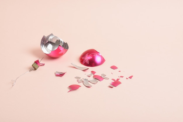 Eine Glasscherben Weihnachtskugel auf einem rosa Hintergrund. Ein kaputtes Weihnachtsspielzeug.