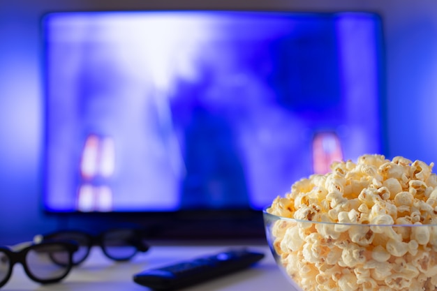 Eine Glasschüssel Popcorn und Fernbedienung.