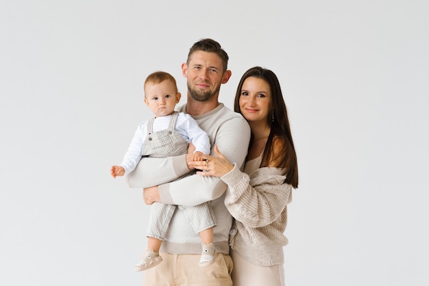 Eine glückliche Drei-Personen-Familie, ein Mann, eine Frau und ein Baby, gehen in einem Studio auf einem weißen Hintergrund für ein Foto vorbei