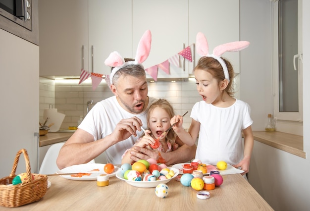 Eine glückliche Familie bereitet sich auf die Osterferien vor, indem sie Ostereier färbt