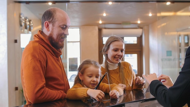 Eine glückliche Familie, die im Hotel an der Rezeption eincheckt