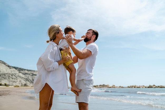 Eine glückliche Familie genießt einen spielerischen Spaziergang am Meer an einem mediterranen Strand