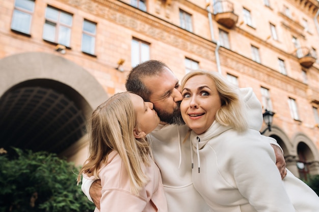 Eine glückliche Familie in weißen Kleidern spaziert durch die Stadt. Ein lustiger Spaziergang.