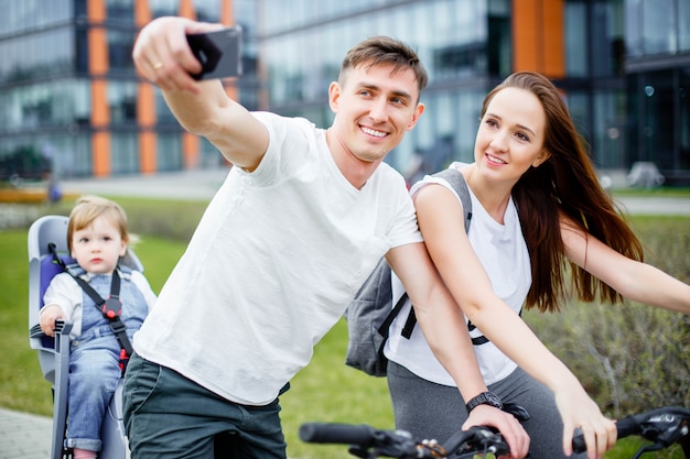 Eine glückliche Familie macht ein Selfie auf einem Smartphone, während sie auf Fahrrädern geht