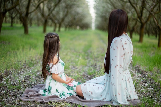 Eine glückliche Familie Mutter und Tochter ruhen sich in Kleidern im Park aus