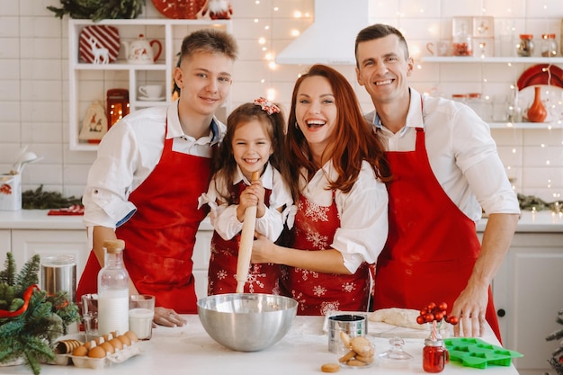 Eine glückliche Familie steht in der Weihnachtsküche und bereitet Teig zum Backen von Keksen vor.