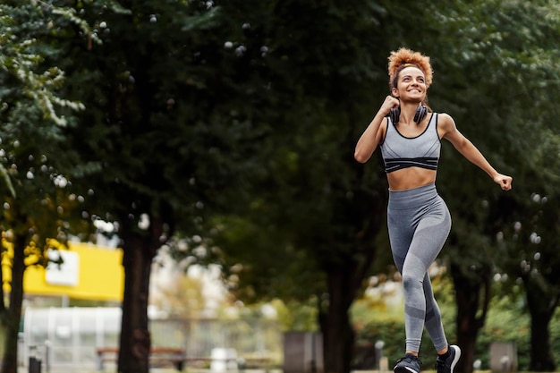 Eine glückliche fitte Läuferin, die mit einem Lächeln im Gesicht auf der Straße läuft