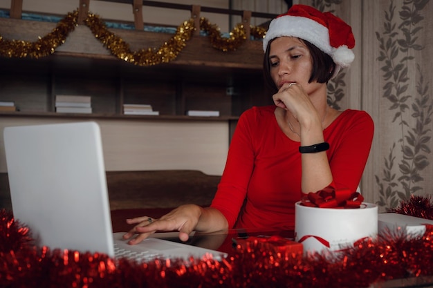 Eine glückliche Frau in einem roten Hemd sitzt vor einem Computerbildschirm