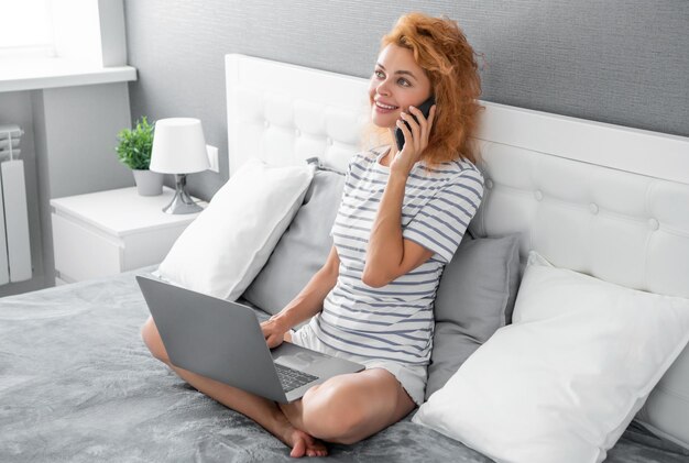 Foto eine glückliche frau spricht zu hause mit dem handy, ein mädchen telefoniert und hält einen offenen laptop auf dem bett.