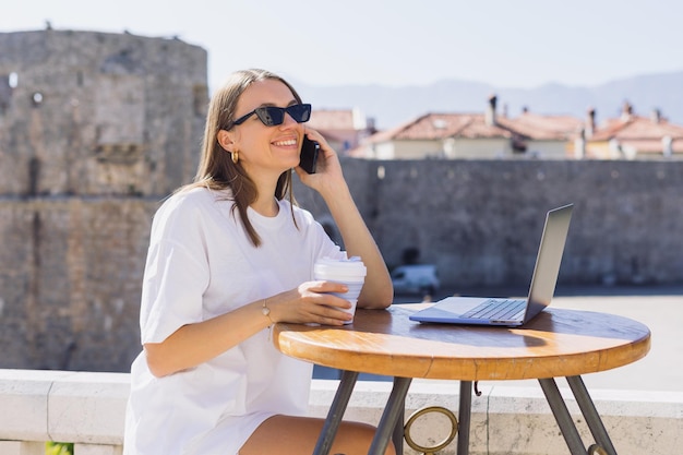 Eine glückliche Frau während eines Gesprächs mit Kollegen Eine Geschäftsfrau in einem Sommercafé Laptop auf dem Tisch