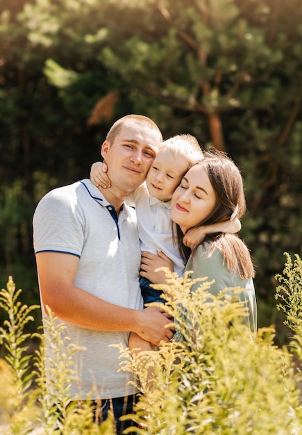 Eine glückliche junge dreiköpfige Familie verbringt Zeit miteinander und lächelt, während sie in der Natur steht