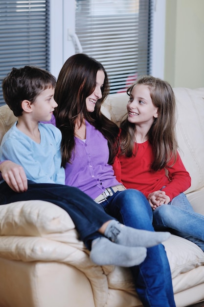 Eine glückliche junge Familie mit Mutter und Kindern hat Spaß und spielt im modernen, neuen Wohnzimmer zu Hause