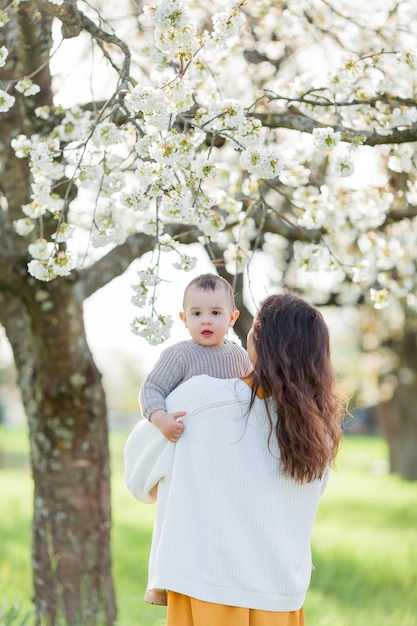 Foto eine glückliche junge familie verbringt zeit im frühlingsblütenpark, mutter und kleiner sohn spielen draußen.