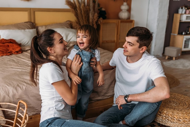 Eine glückliche junge Familie verbringt Zeit zusammen in einem Wohngebäude Eine schöne glückliche Familie verbringt Zeit zusammen zu Hause Ein junges Ehepaar mit ihrer süßen Tochter Die Familie verbringt Zeit zu Hause